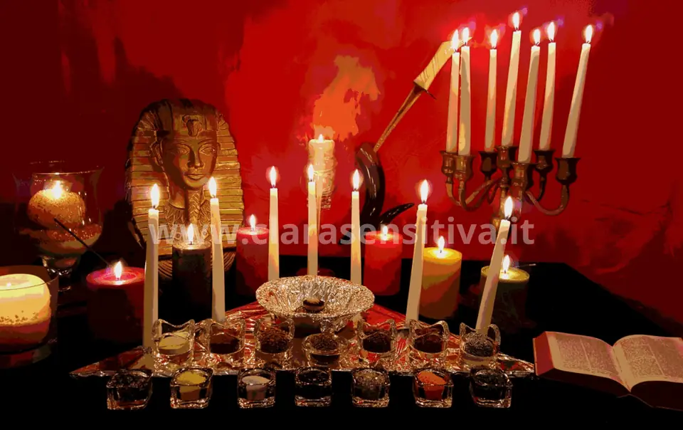 Tavolo rituale con candele accese, erbe e incensi